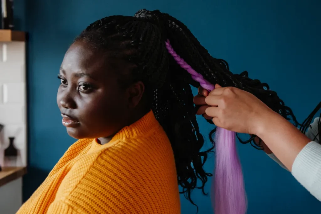A black woman getting hair braider on the salon.
