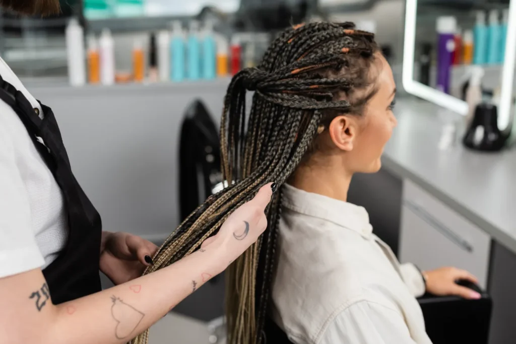 A young african black woman getting her braided hair checked by the hairdresser.