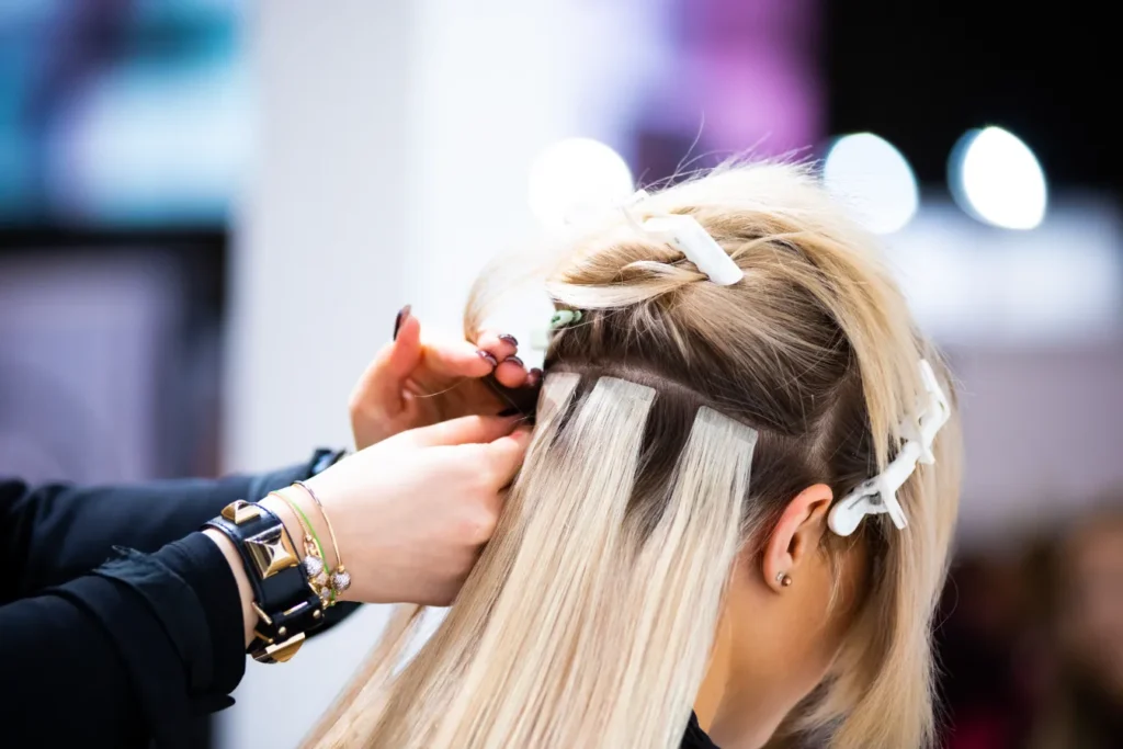 A hairdresser attaching the hair extension onto the client's hair.